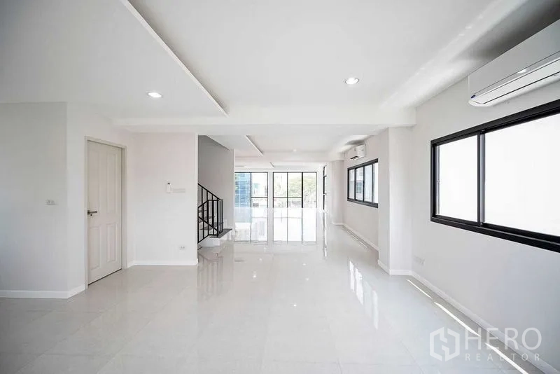 带办公室的家 出租在Suan Luang, Bangkok - 明亮开放的办公楼层，白色地砖、阳台玻璃门与侧边楼梯。