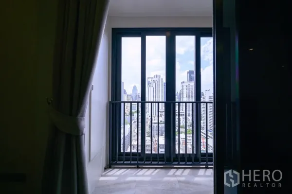 Condominium for rent in Watthana, Bangkok - Balcony with floor-to-ceiling sliding doors framing a Bangkok skyline view.
