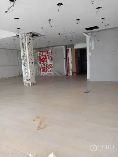 Retail Space for rent in Watthana, Bangkok - Spacious shop floor with hanging ceiling wiring and a concrete pillar ready for tenant fit-out.