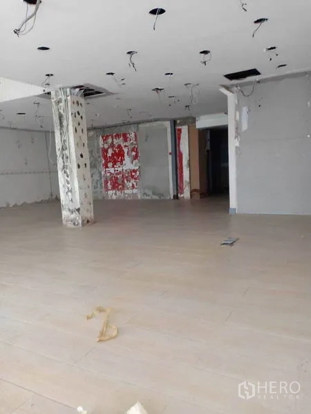 Retail Space for rent in Watthana, Bangkok - Spacious shop floor with hanging ceiling wiring and a concrete pillar ready for tenant fit-out.