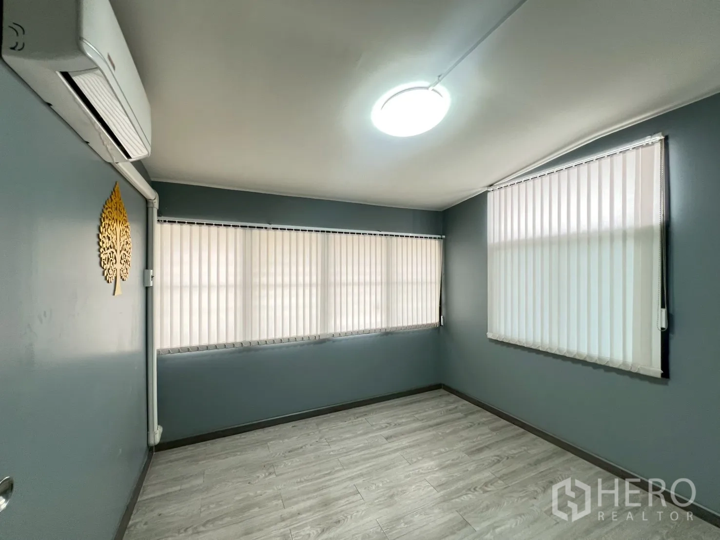 Detached House for rent or sale in Wang Thonglang, Bangkok - Bright room with grey walls, wood‑look flooring, blinds and wall‑mounted air conditioner.