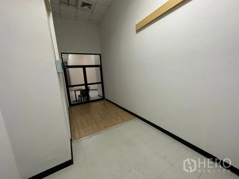 办公空间 出租 - 室内走廊，带小型抬高平台与黑框室内窗，墙面中性色调。