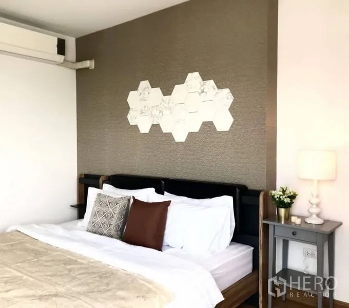 公寓 出租或出售在Huai Khwang, Bangkok - 采光良好的卧室，质感特色墙与六边形装饰、床头柜。