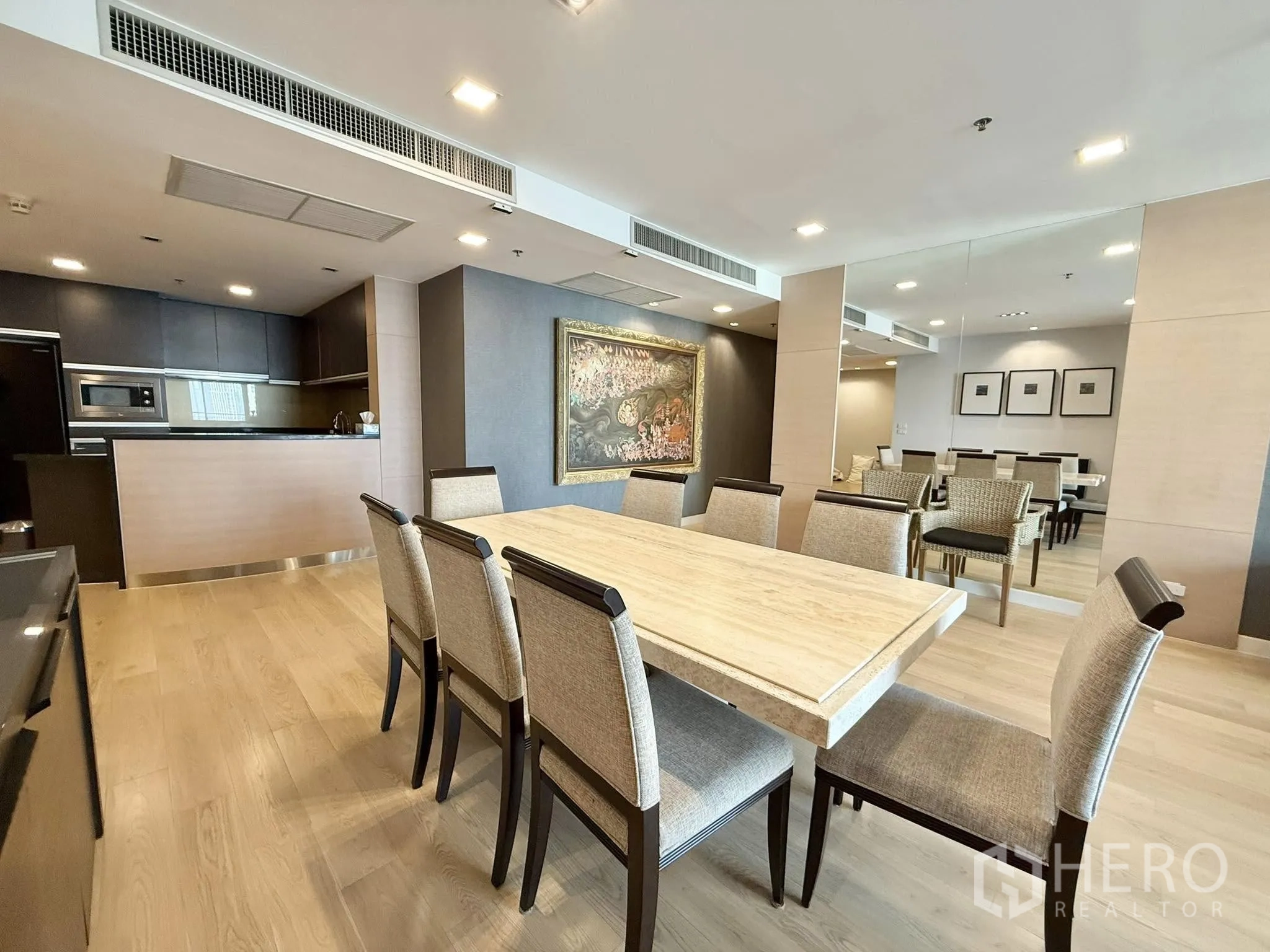 Condominium for rent or sale in Sathon, Bangkok - Eight-seat dining table beside a mirrored wall and modern open kitchen.