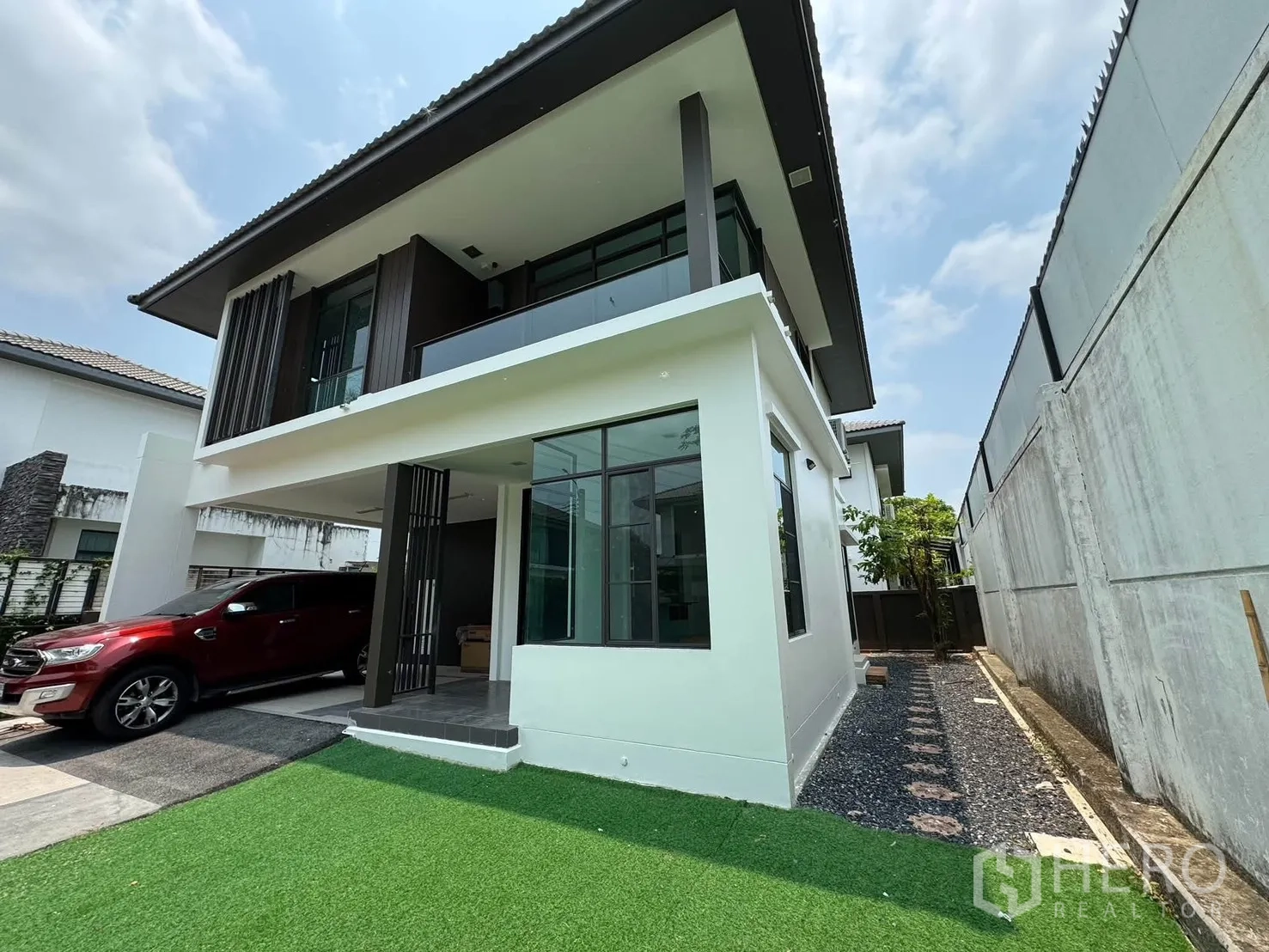 Detached House for rent in Prawet, Bangkok - Modern two-storey house exterior with a covered carport and lawn.