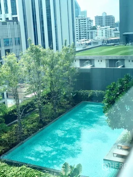 公寓 出租在Watthana, Bangkok - 公寓户外泳池，被绿树环绕并可见周边城市建筑。
