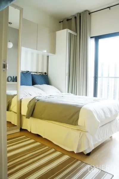 Condominium for rent in Phaya Thai, Bangkok - Bright bedroom with white bed, mirrored wardrobe, striped rug and balcony glass door.