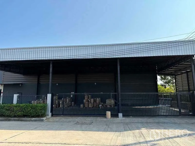 Factory for rent in Samut Prakan - Front loading bay with roller shutters and security fencing.