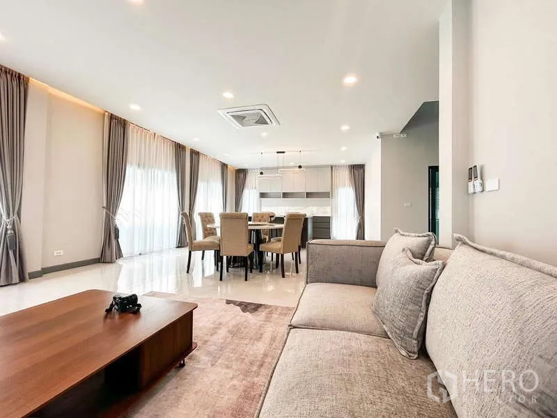Detached House for rent in Bang Phli, Samut Prakan - View from sofa to dining and kitchen with floor-to-ceiling curtains, pendant lights and cassette air-con.