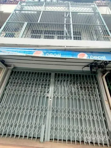 Shophouse for rent in Khlong Toei, Bangkok - Street-level view of a multi-storey shophouse with metal folding gate, balcony grilles and a blue awning in Khlong Toei near BTS Phrom Phong.