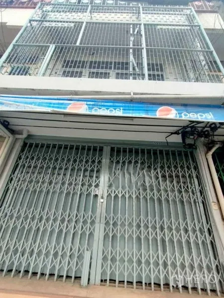 Shophouse for rent in Khlong Toei, Bangkok - Street-level view of a multi-storey shophouse with metal folding gate, balcony grilles and a blue awning in Khlong Toei near BTS Phrom Phong.