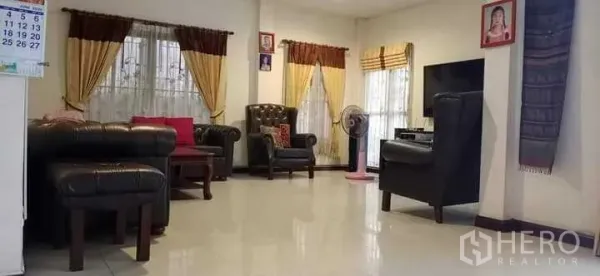 独立式住宅 出售在Prawet, Bangkok - 明亮客厅，皮沙发、电视与大窗帘窗户