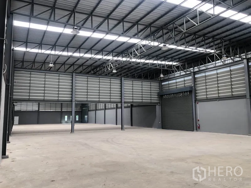 Factory for rent or sale in Bang Bo, Samut Prakan - Warehouse interior showing roller shutter loading door and steel truss roof.