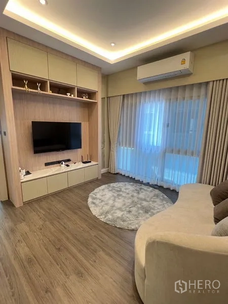 独立式住宅 出售在Bang Kapi, Bangkok - 二层家庭室，定制电视柜、弧形沙发与阳台玻璃门。