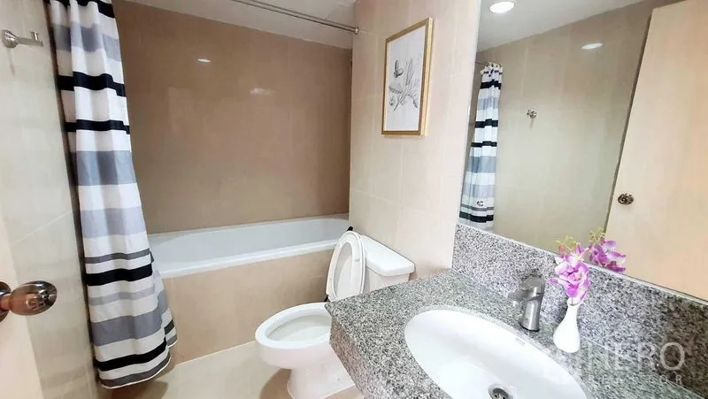 公寓 出售在Bang Kho Laem, Bangkok - 浴室配浴缸、条纹浴帘、花岗岩台面与大镜子。