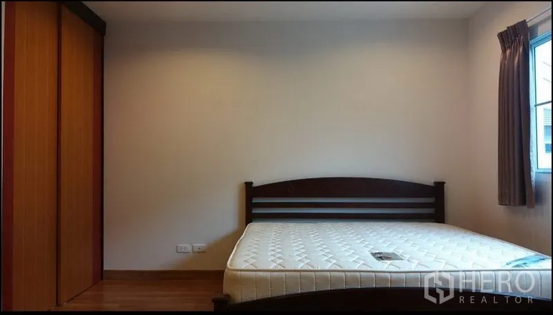 Townhouse for rent in Suan Luang, Bangkok - Simple bedroom with double bed, wardrobe, and a window dressed with brown curtains.
