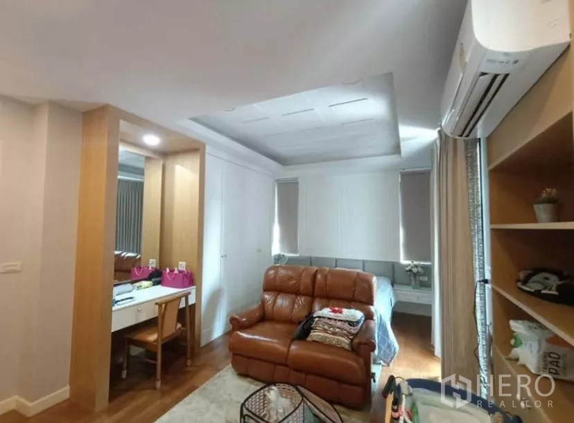 Townhouse for rent in Yan Nawa, Bangkok - Bedroom seating nook with leather sofa, vanity, and built-in wardrobes.