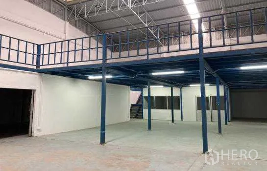 Warehouse for rent or sale in Prawet, Bangkok - Close view of the mezzanine structure with lighting and stairs inside the warehouse.