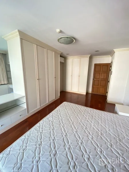 房间 出租在Watthana, Bangkok - 卧室一角，多个内置衣柜、木门与光亮木地板。