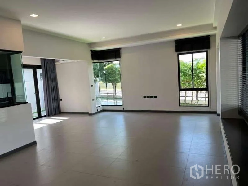 独立式住宅 出租或出售在Bang Phli, Samut Prakan - 客厅转角大窗，视野开阔可见花园景观。