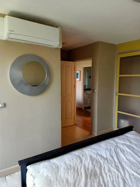 Condominium for rent in Khlong Toei, Bangkok - Bedroom detail showing wall-mounted air conditioner and doorway to the hall.