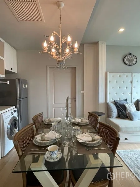 Condominium for rent in Bangkok - Open-plan dining and living zone with chandelier lighting and plush sofa.