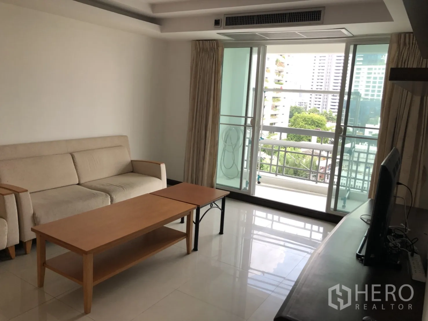 Condominium for rent in Watthana, Bangkok - Living room opening to a balcony with city and greenery views.