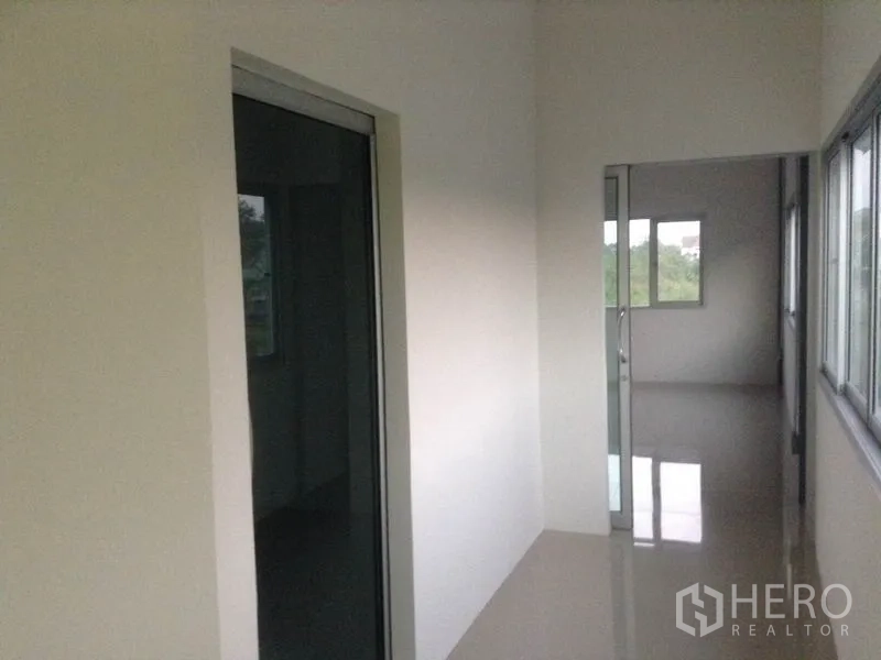 Warehouse for rent in Bang Kapi, Bangkok - Upper-floor corridor with windows and glass doors connecting office rooms overlooking greenery.
