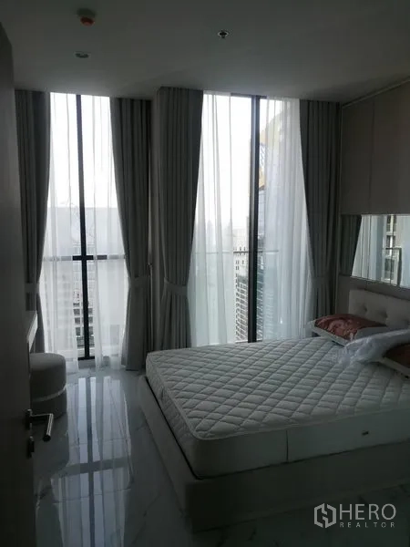 公寓 出租在Pathum Wan, Bangkok - 转角卧室，通高落地窗与城市景观，配大床与浅色窗帘