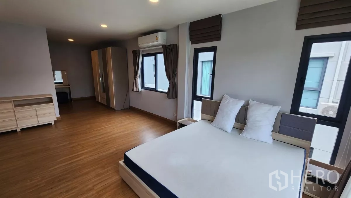 Detached House for rent in Bang Phli, Samut Prakan - Master bedroom corner showing bed, wardrobe, dressing desk, multiple windows and air conditioning.