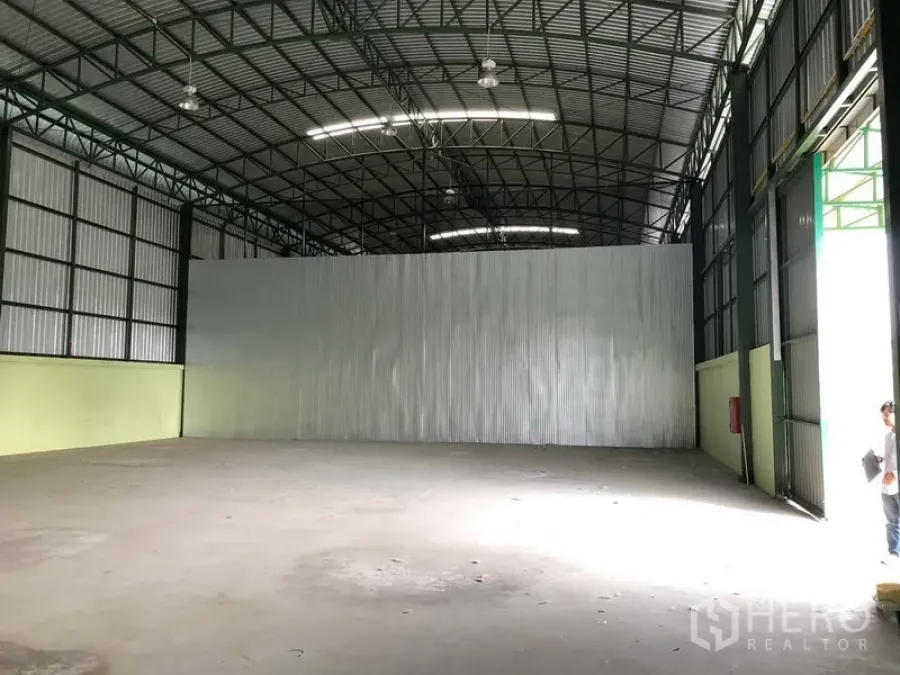 货栈 出租在Lat Krabang, Bangkok - 室内朝隔墙视角，右侧大型滑门，混凝土地面与壁挂式灭火器。