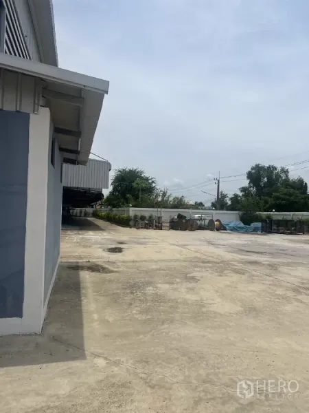 Factory for sale in Lat Lum Kaeo, Pathum Thani - Expansive concrete yard around the factory with boundary wall and outdoor storage area.