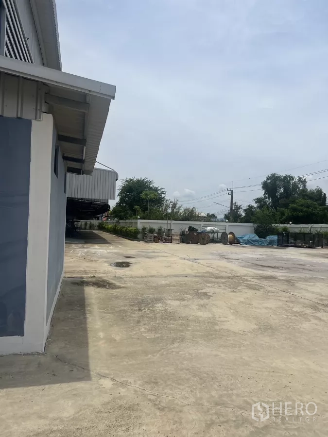 Factory for sale in Lat Lum Kaeo, Pathum Thani - Expansive concrete yard around the factory with boundary wall and outdoor storage area.