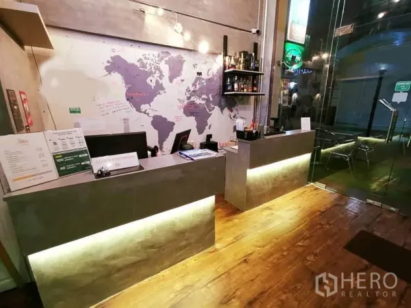 Office Space for rent or sale in Bang Rak, Bangkok - Industrial-style reception with concrete counters, a world map mural, and a glass entry.