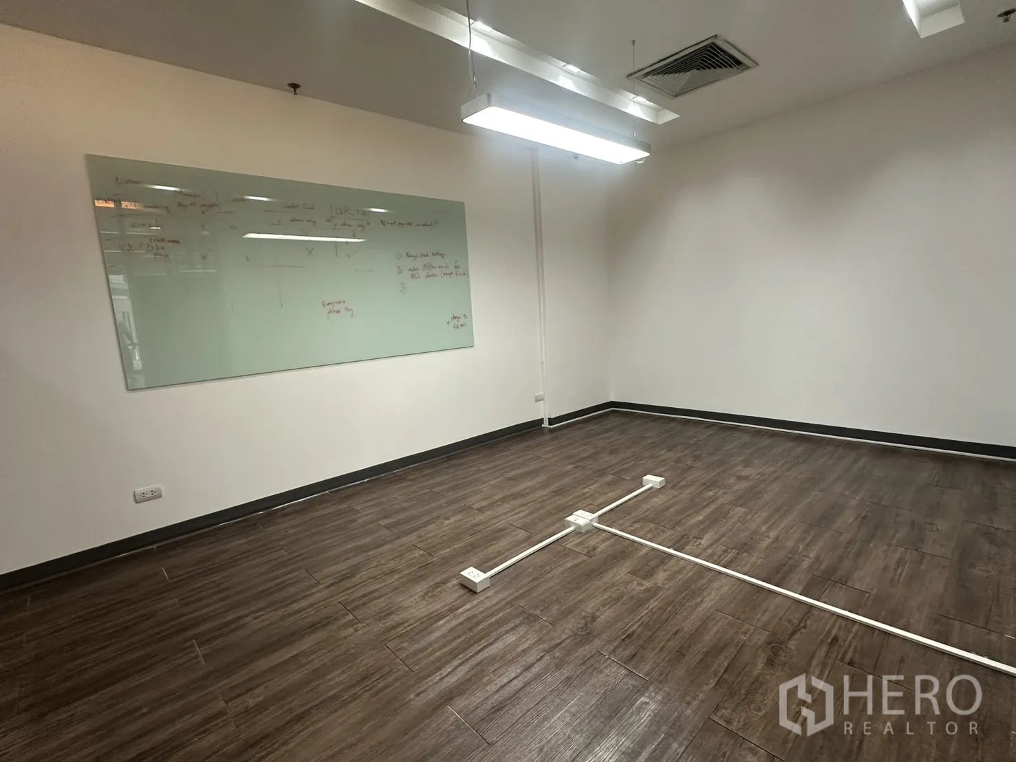 办公室 for rent in Pathum Wan, Bangkok - 带大型玻璃白板的会议室，木纹地板与线性吊顶照明。