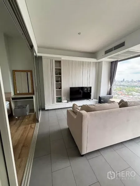 Condominium for rent or sale in Phaya Thai, Bangkok - Living area with built‑in TV wall and large window, connected to a bedroom by a sliding glass door.