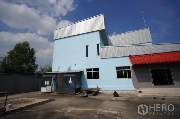 Factory for sale in Khlong Luang, Pathum Thani - Blue factory building with saw-tooth roof and loading dock in Khlong Luang, Pathum Thani.