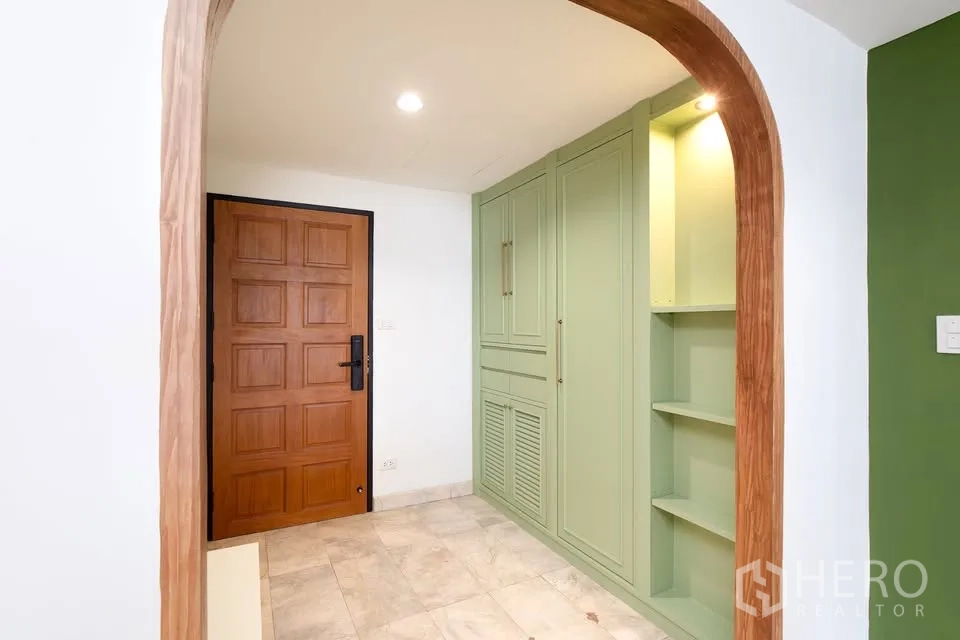 公寓 for rent in Watthana, Bangkok - 入口走廊设木门、拱形门框与薄荷绿嵌入式柜体。