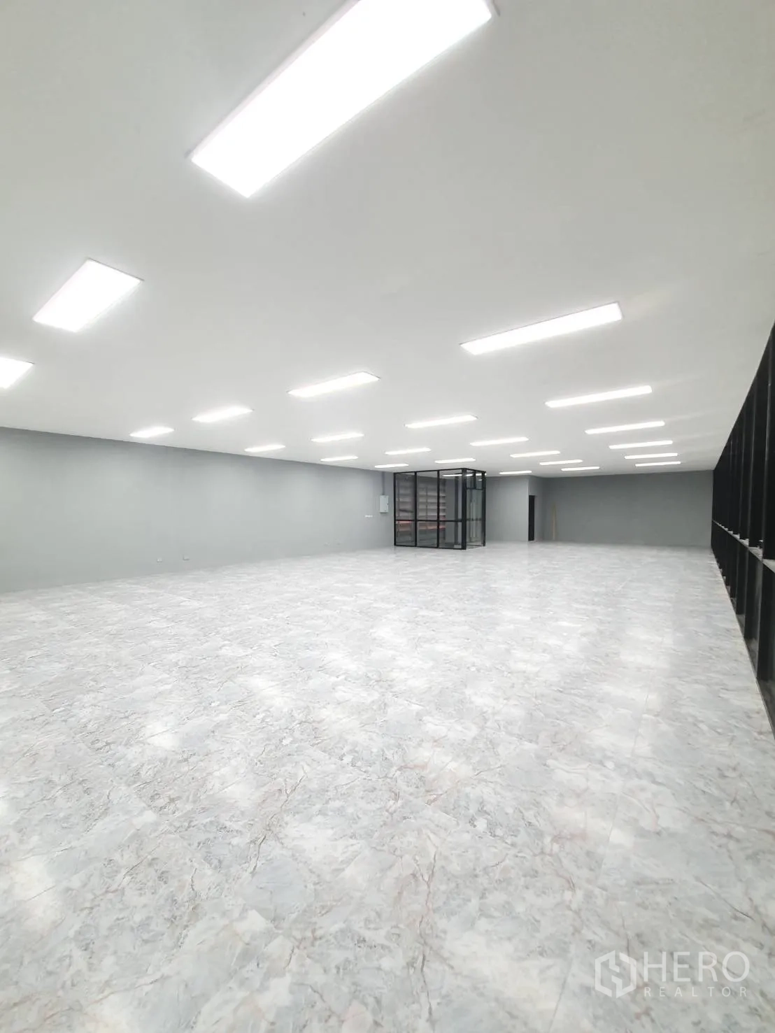 Warehouse for rent in Sai Mai, Bangkok - Wide office area with bright LED lights, marble-style tiles and black-framed glass partition.