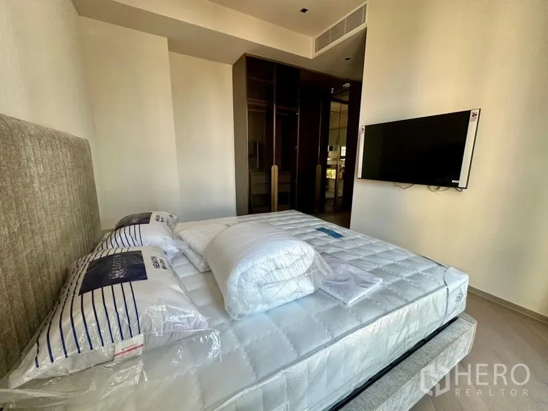 Condominium for rent - Bedroom angle showing bed, glossy wardrobe and TV on wall.