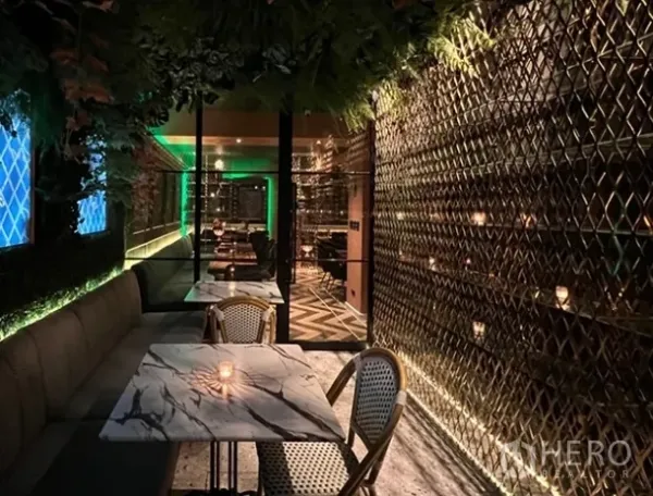 零售空间 出租在Bang Rak, Bangkok - 狭长用餐走廊，配大理石餐桌、藤椅、金色格栅墙与垂悬绿植。