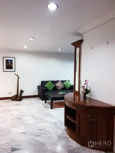 公寓 出租或出售在Watthana, Bangkok - 客厅另一角度，沙发、茶几与弧形木质柜。