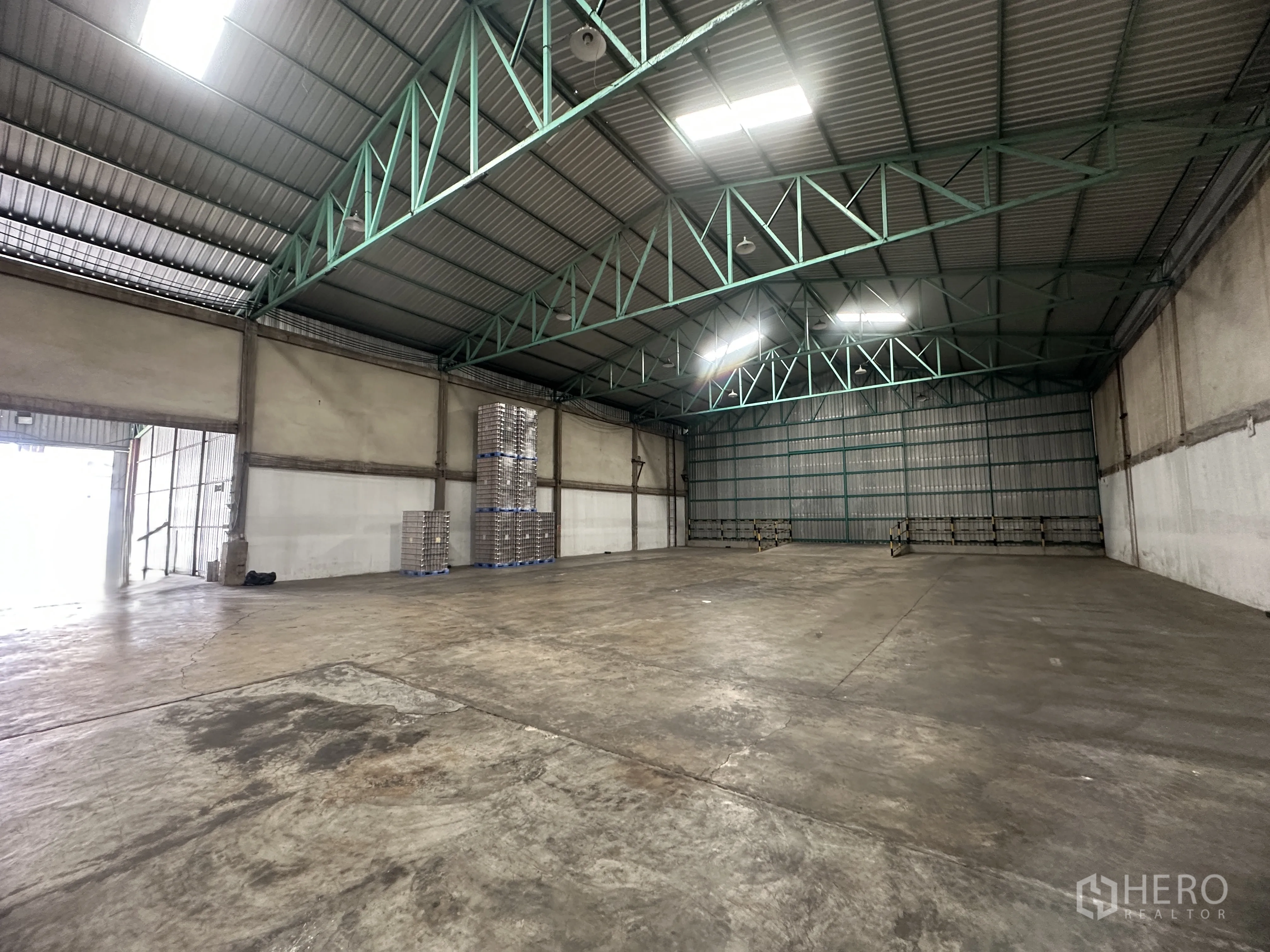 Warehouse for rent in Mueang Pathum Thani, Pathum Thani - Spacious warehouse interior with high steel truss roof, skylights, and smooth concrete flooring.