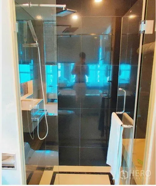 Condominium for rent in Ratchathewi, Bangkok - Modern bathroom featuring a frameless glass shower with rain showerhead and sleek fixtures.