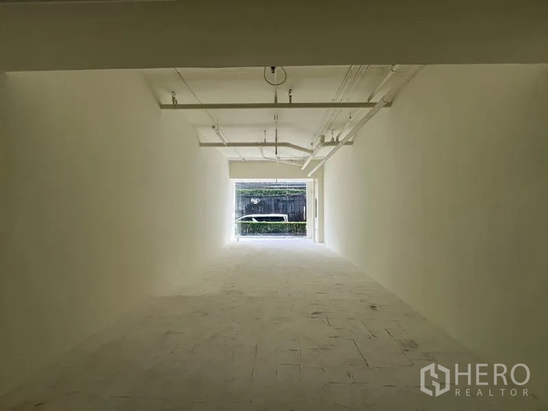 Retail Space for rent in Watthana, Bangkok - View from the rear toward the glass frontage with greenery visible outside at the street side.