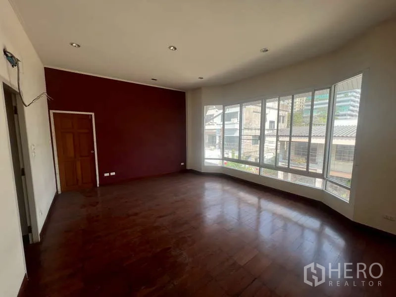 Detached House for rent in Watthana, Bangkok - Large upper room with bay corner windows and maroon feature wall.