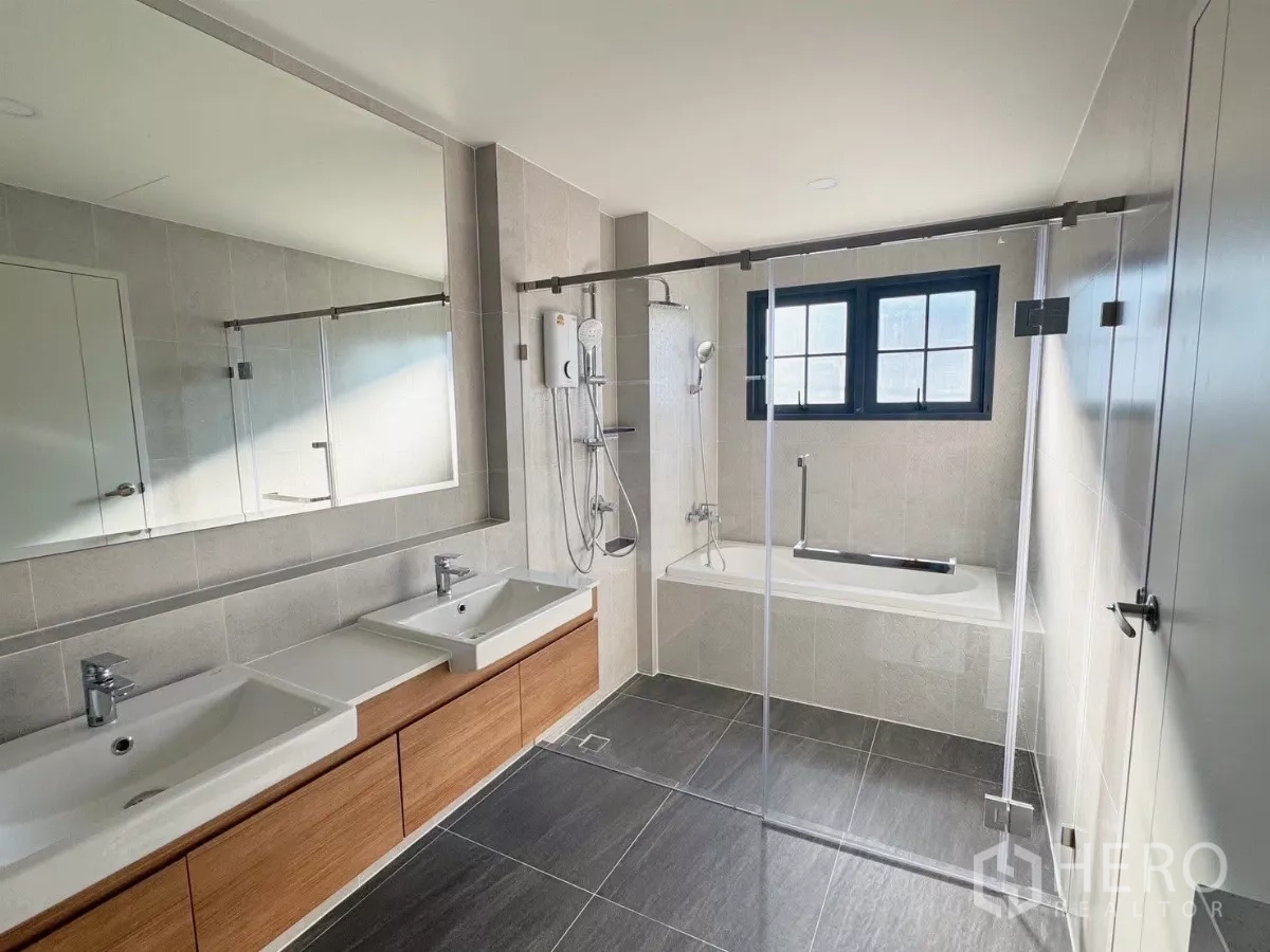 Detached House for rent or sale in Bang Phli, Samut Prakan - Master bathroom with double sinks, bathtub and glass shower enclosure.