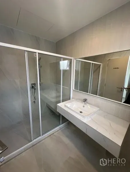 Detached House for rent - Modern bathroom with a glass-enclosed shower, wall-mounted sink, and large mirror.