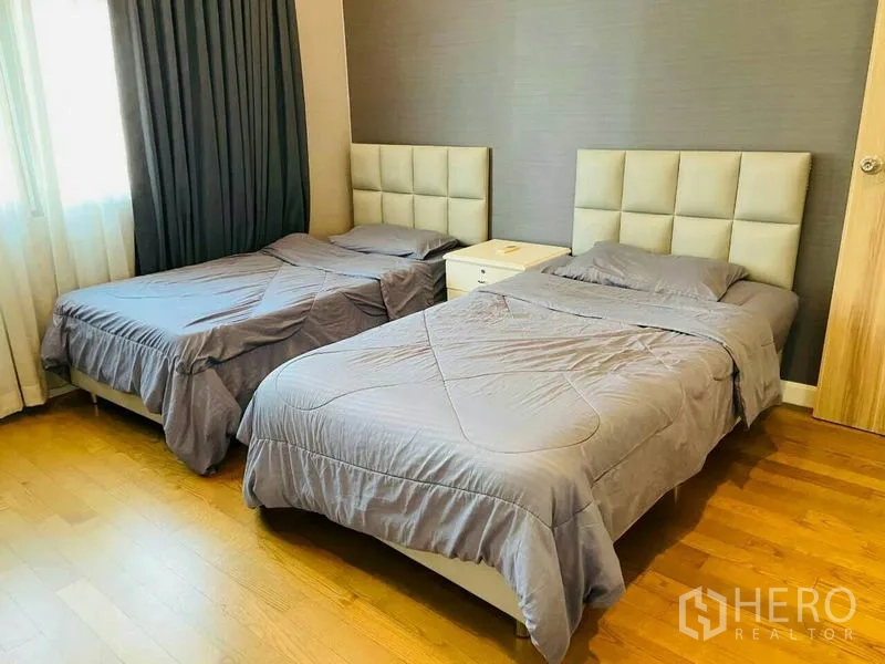 公寓 出租在Watthana, Bangkok - 次卧配两张单人床，软包床头与木地板。