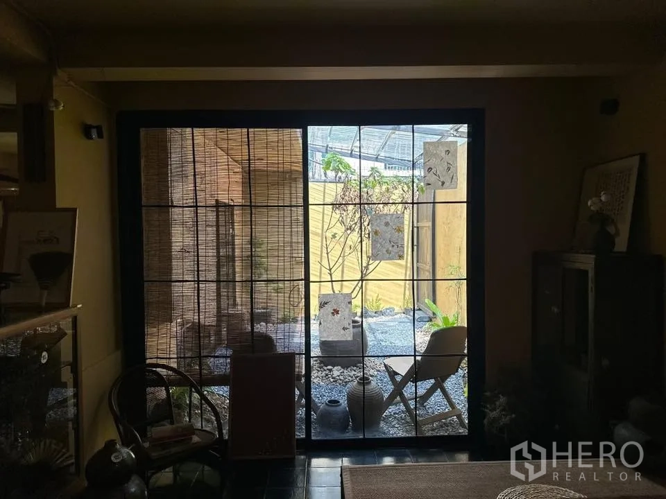 Retail Space for rent in Khlong Toei, Bangkok - View through a large sliding door to a small patio with chairs and decorative pots.